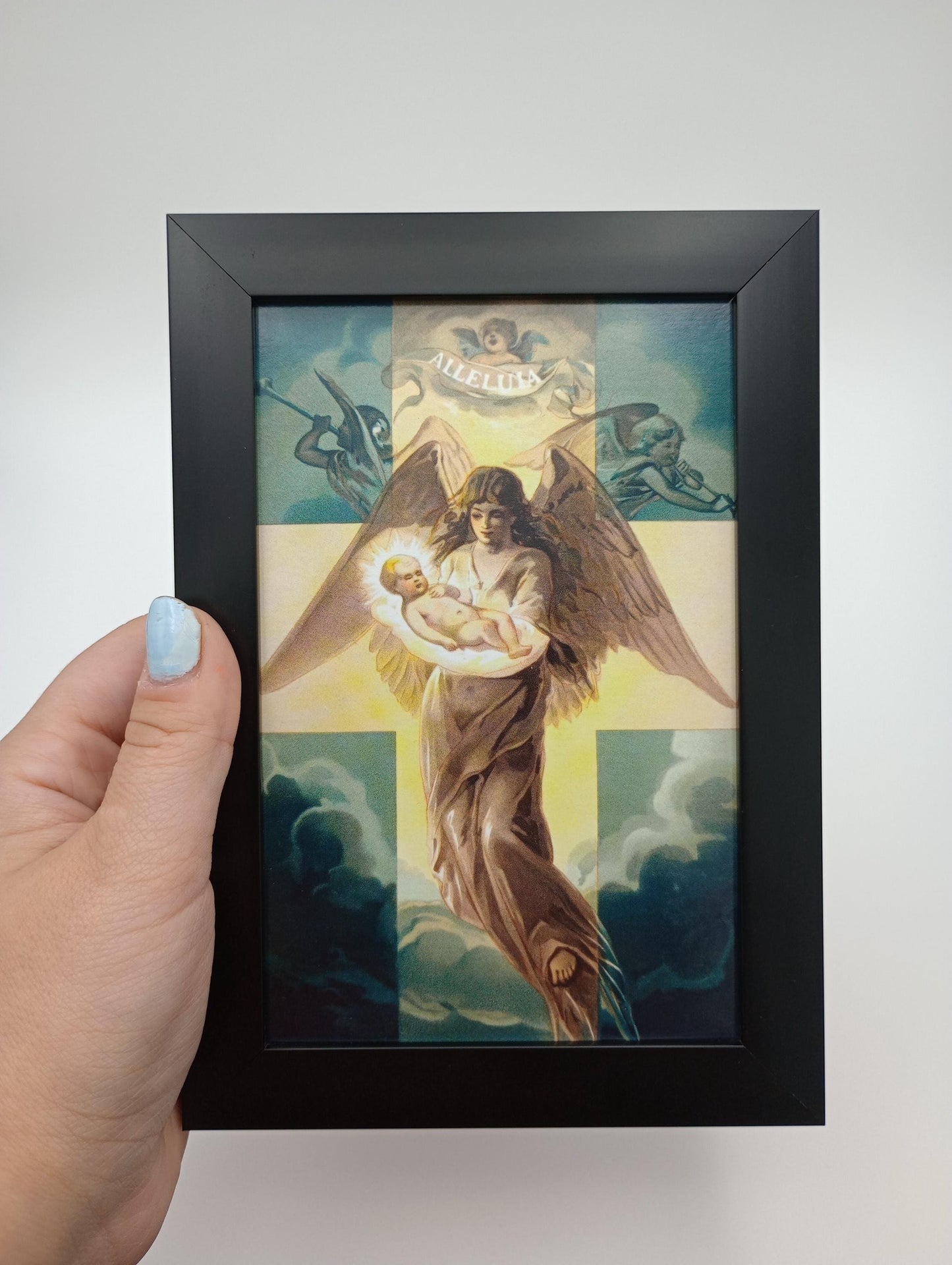 a hand holding a framed painting of an angel