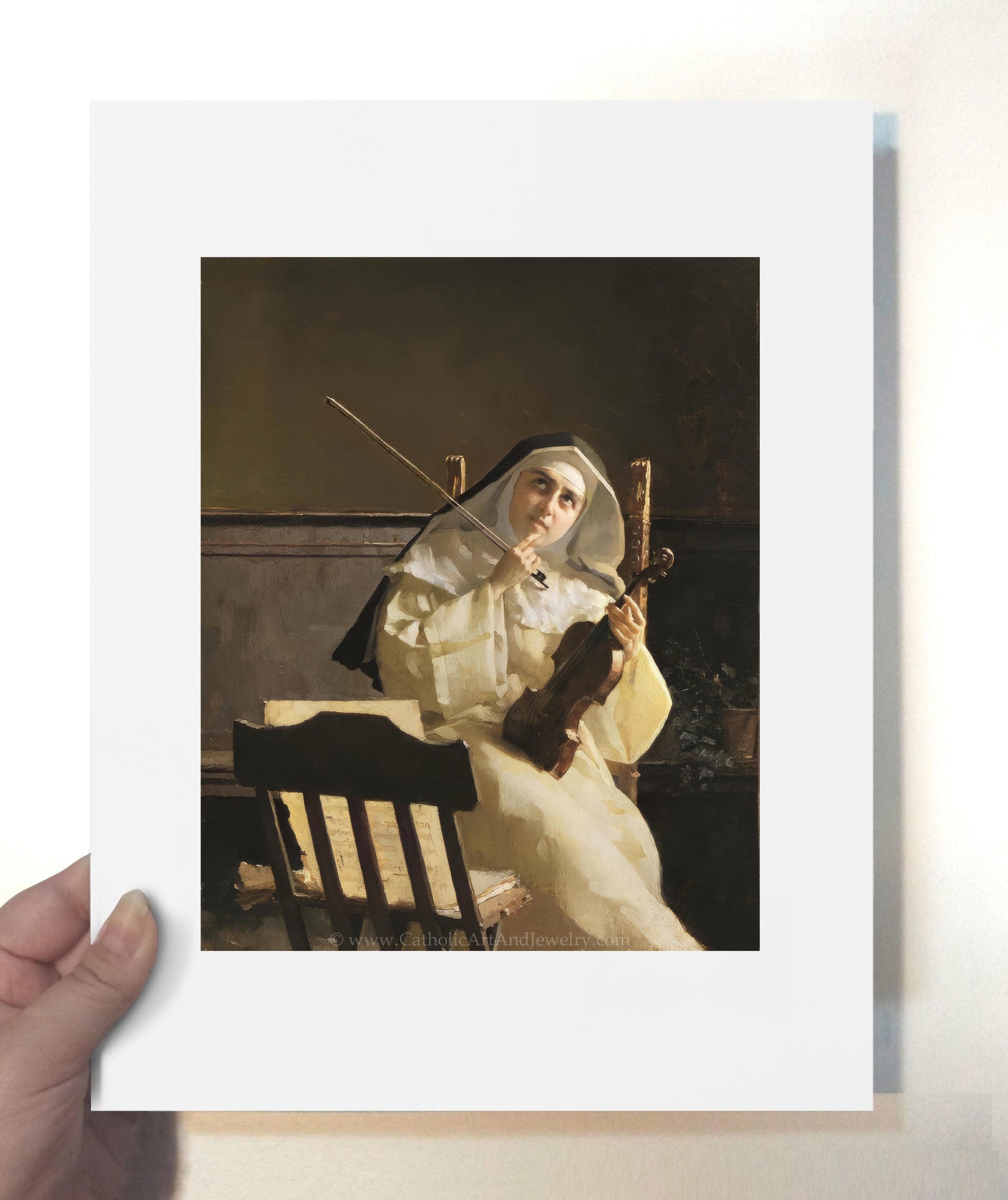 a person holding a picture of a nun sitting on a bench