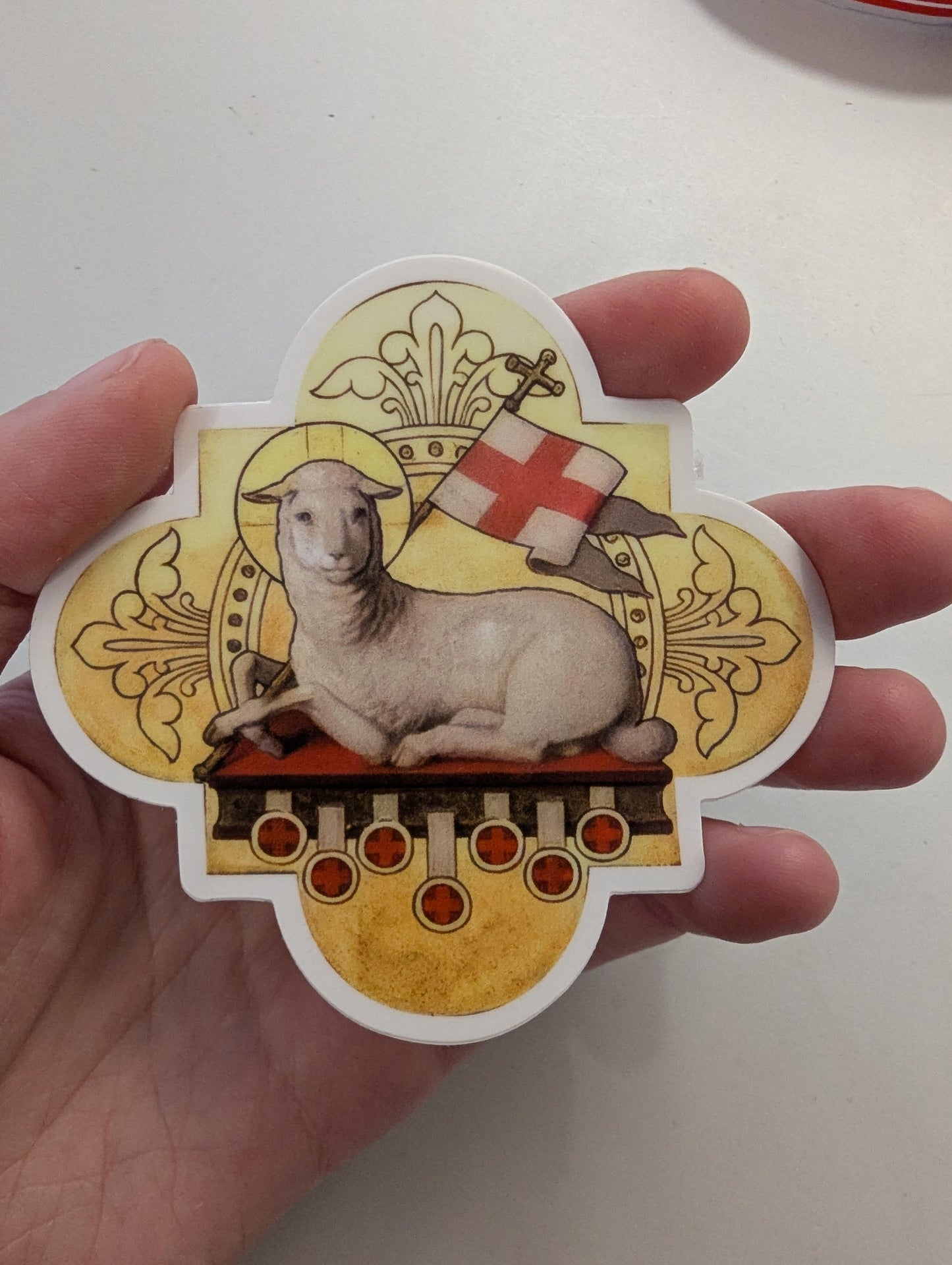 a hand holding a sticker with a picture of a sheep on it