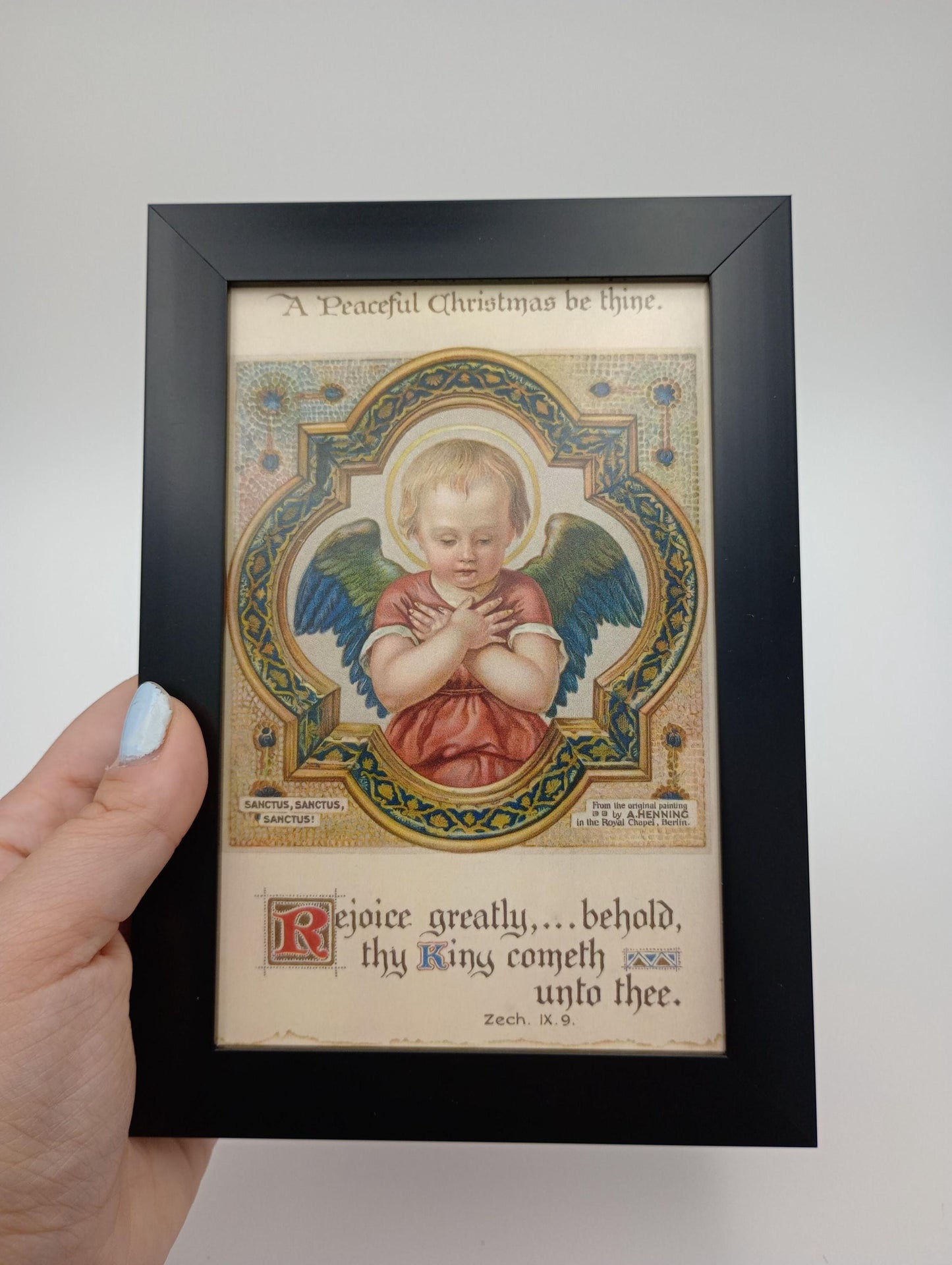 a hand holding a framed picture of an angel