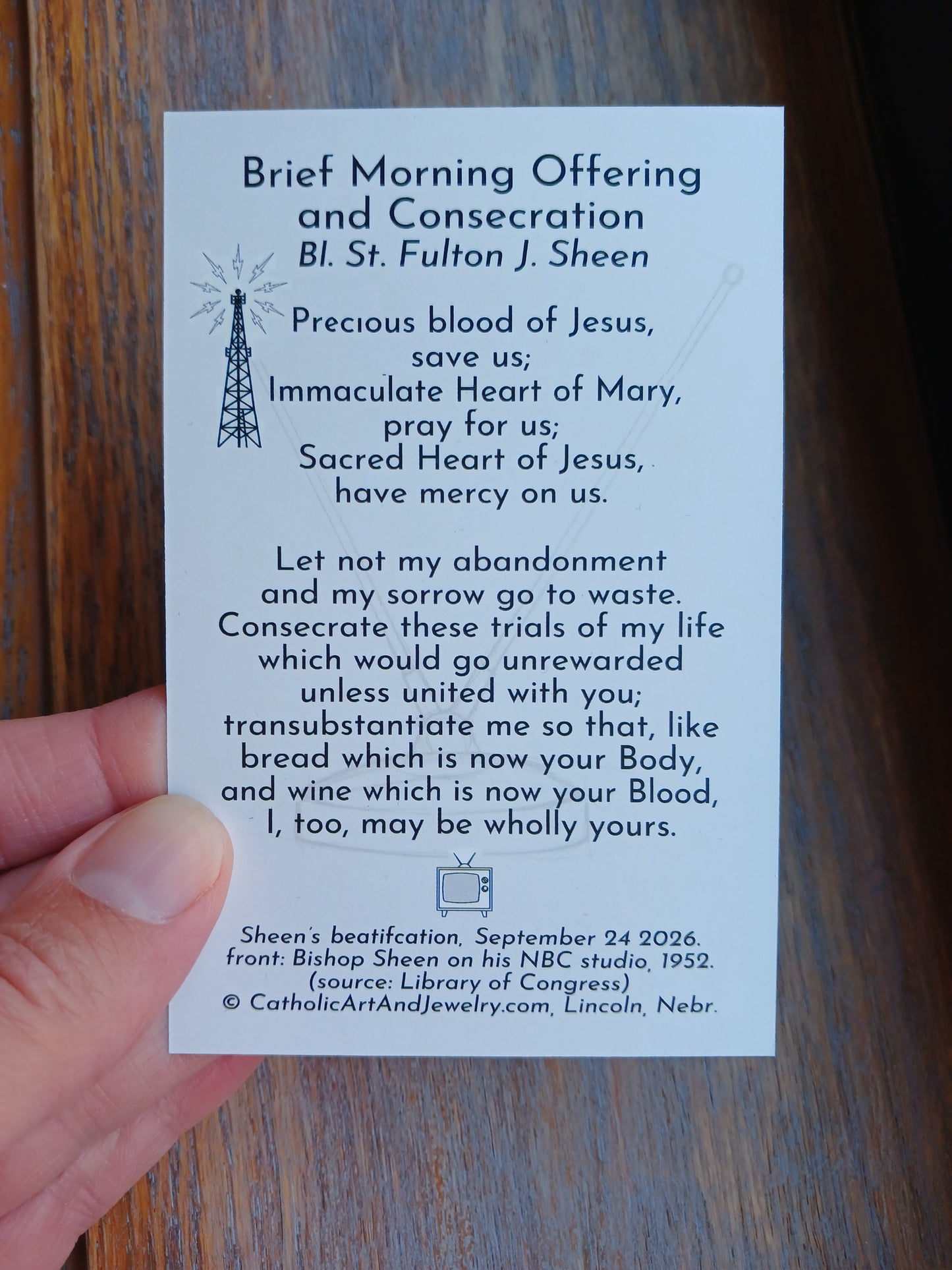 a person's hand holding a card with text and a small illustration of a radio tower.