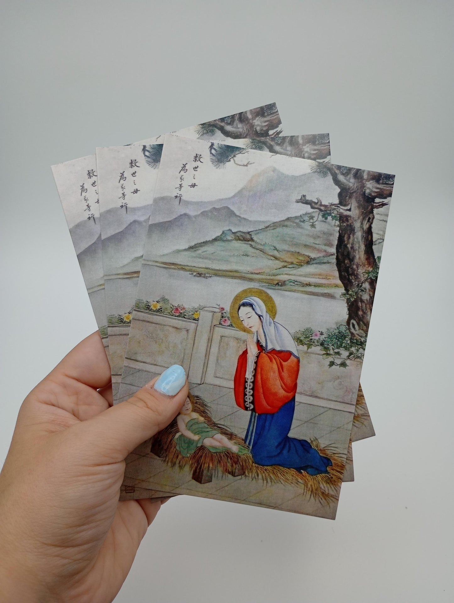a hand holding a set of four religious cards