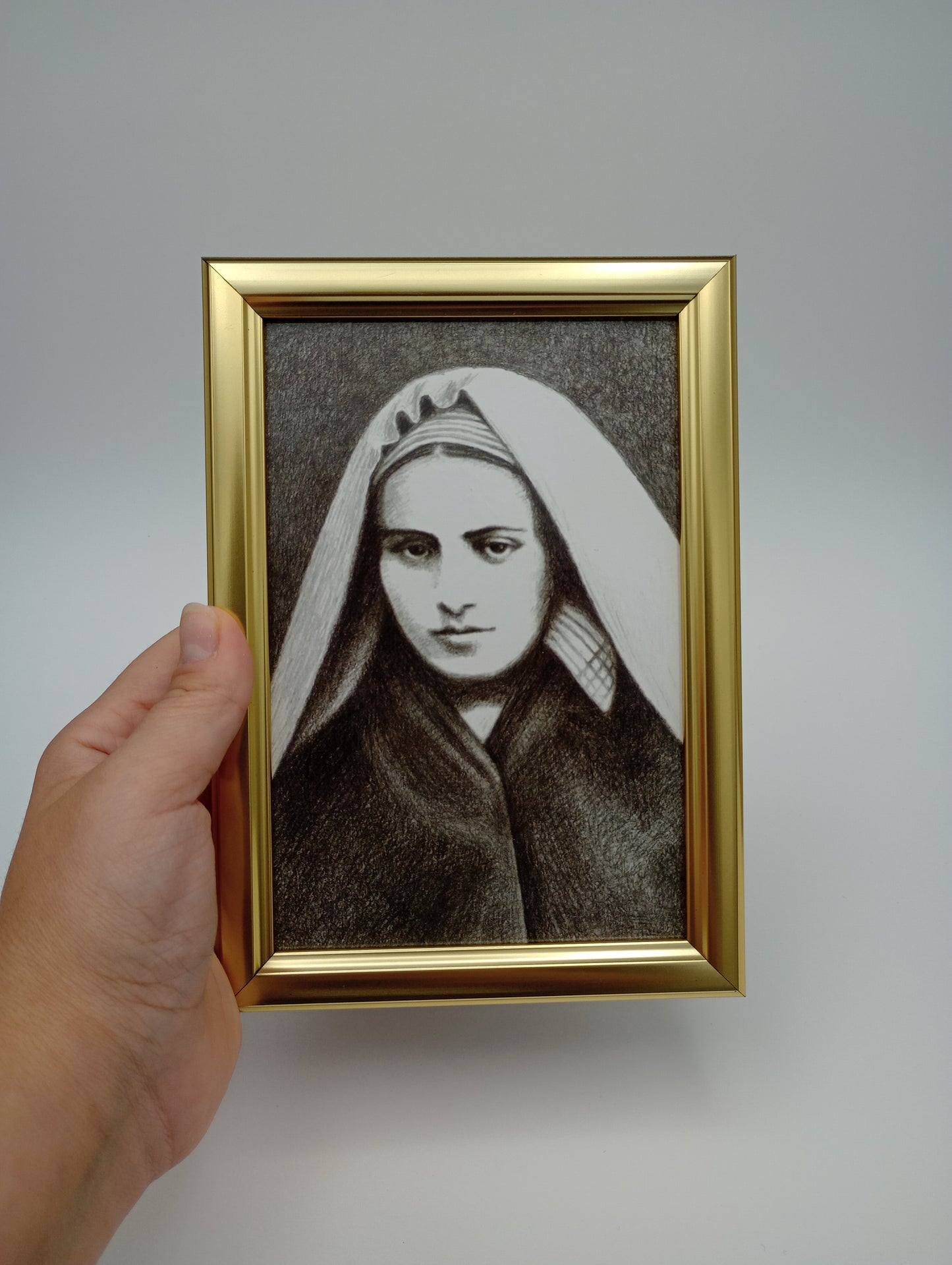 a hand holding a picture of a woman in a hat