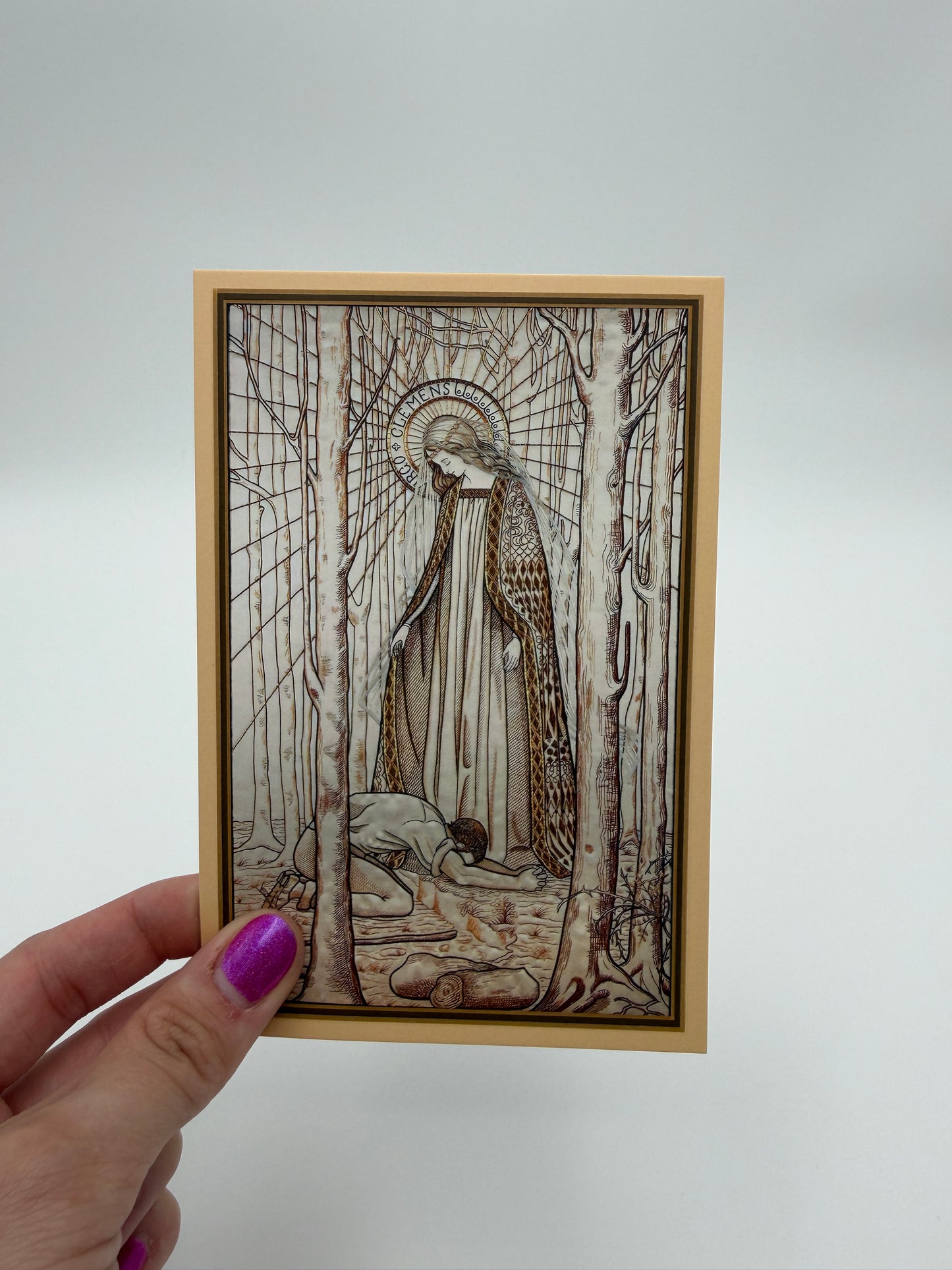 A hand holding a framed print with an intricate, abstract illustration depicting a figure in a landscape with a bird-like creature.