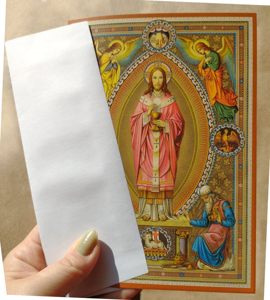 A hand holding a white piece of paper in front of a colorful, ornate religious card featuring a figure of Jesus Christ.