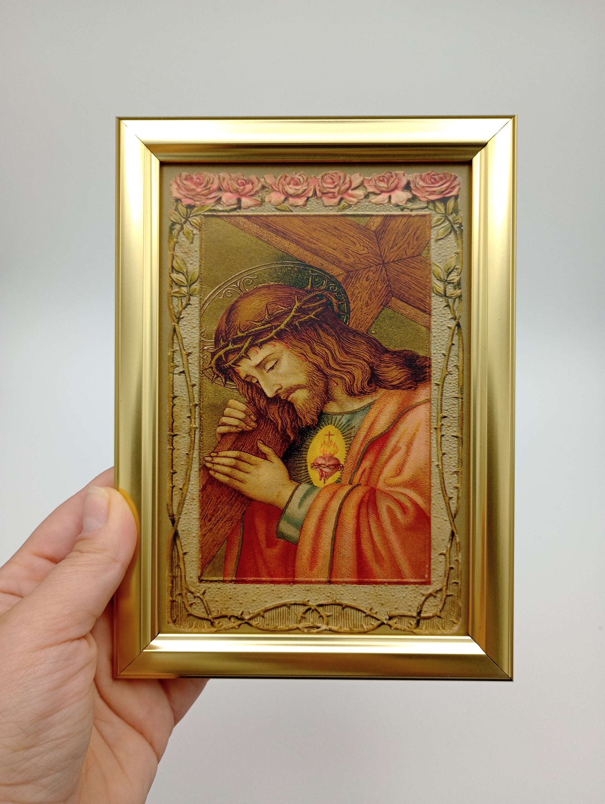 a hand holding a picture of a woman with a cross