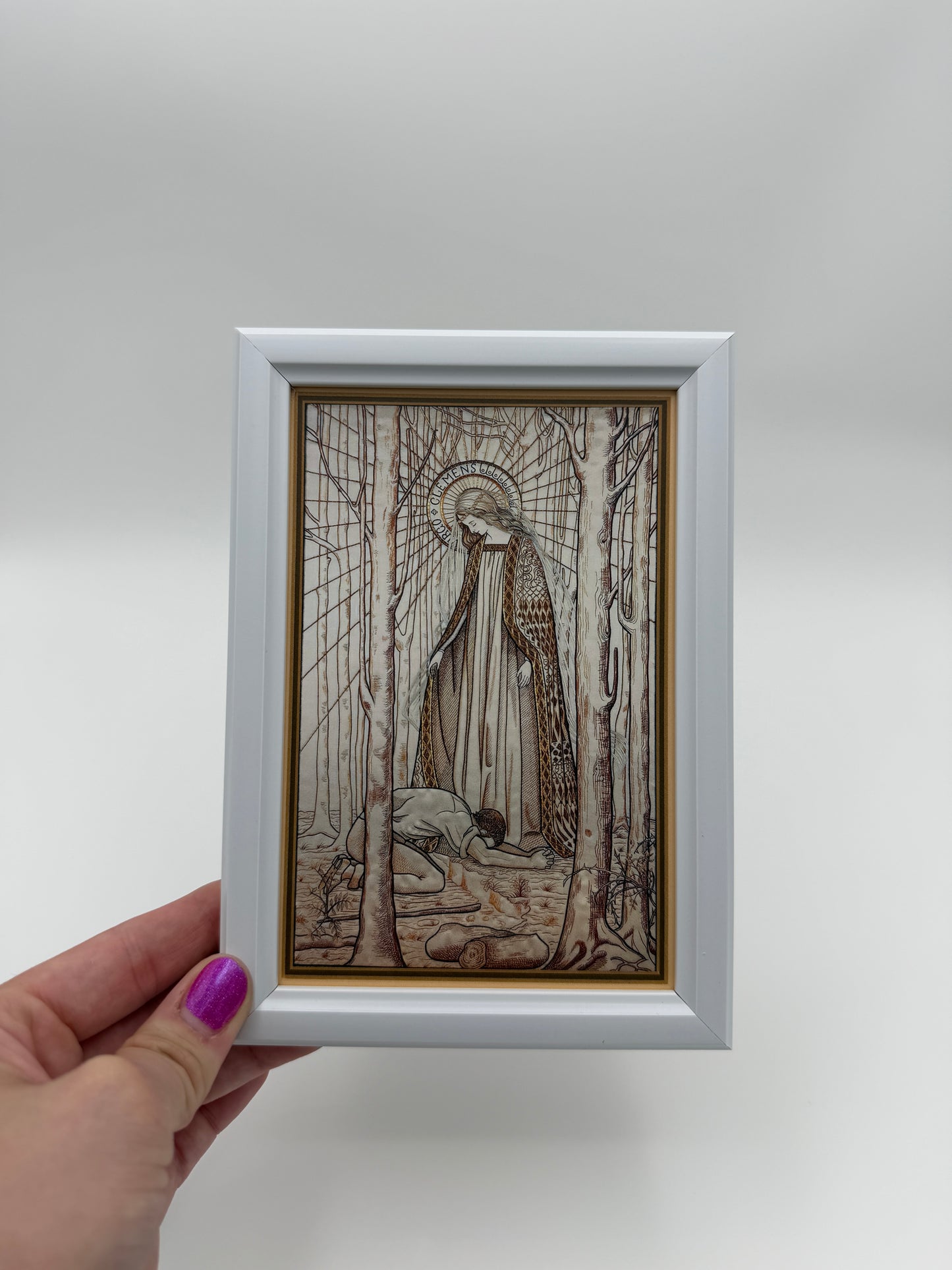 A hand is holding a small framed picture with an intricate, abstract drawing on the inside.