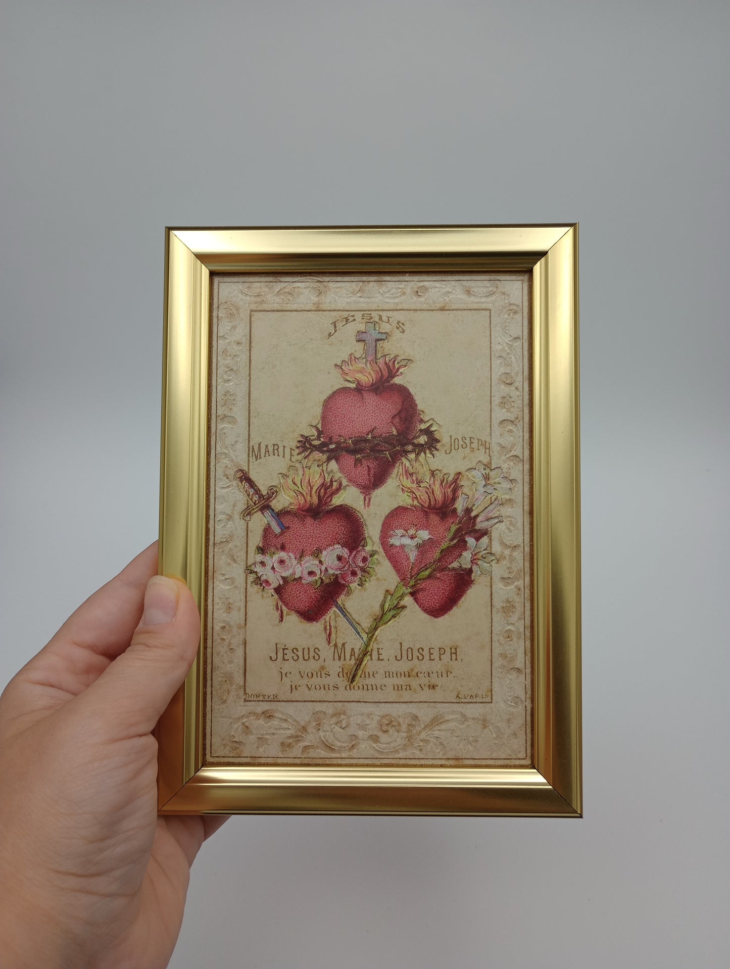 a hand holding a framed picture of flowers