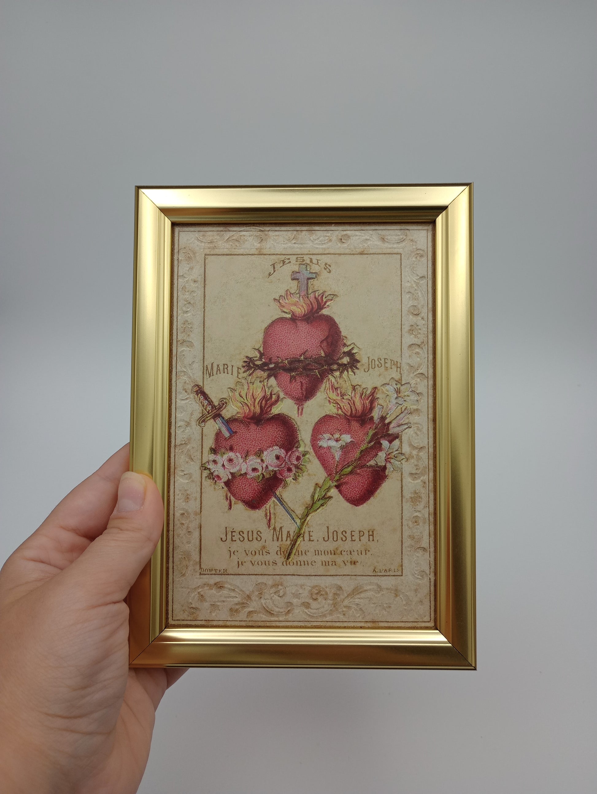 a hand holding a framed picture of flowers