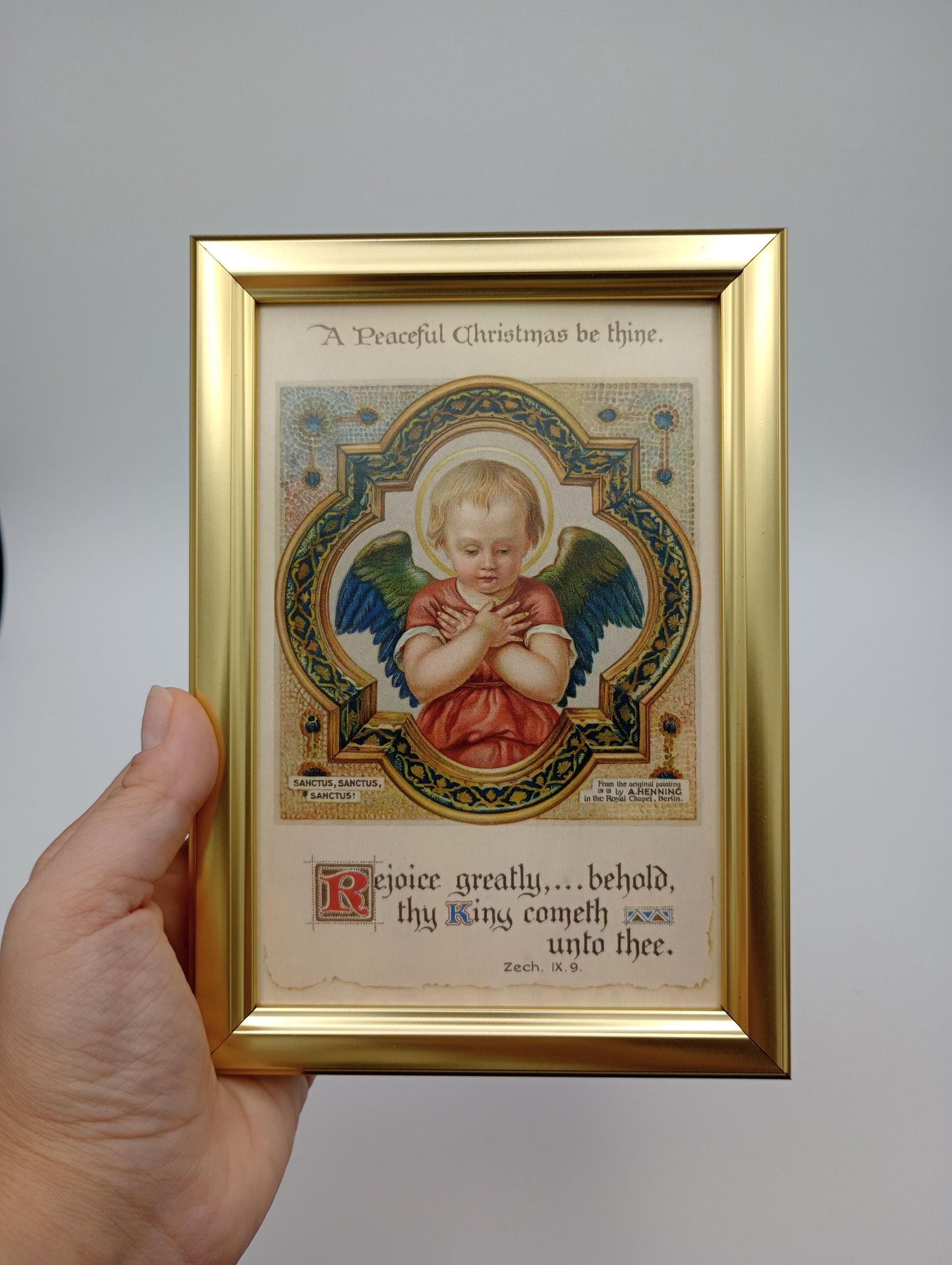 a hand holding a framed picture of an angel