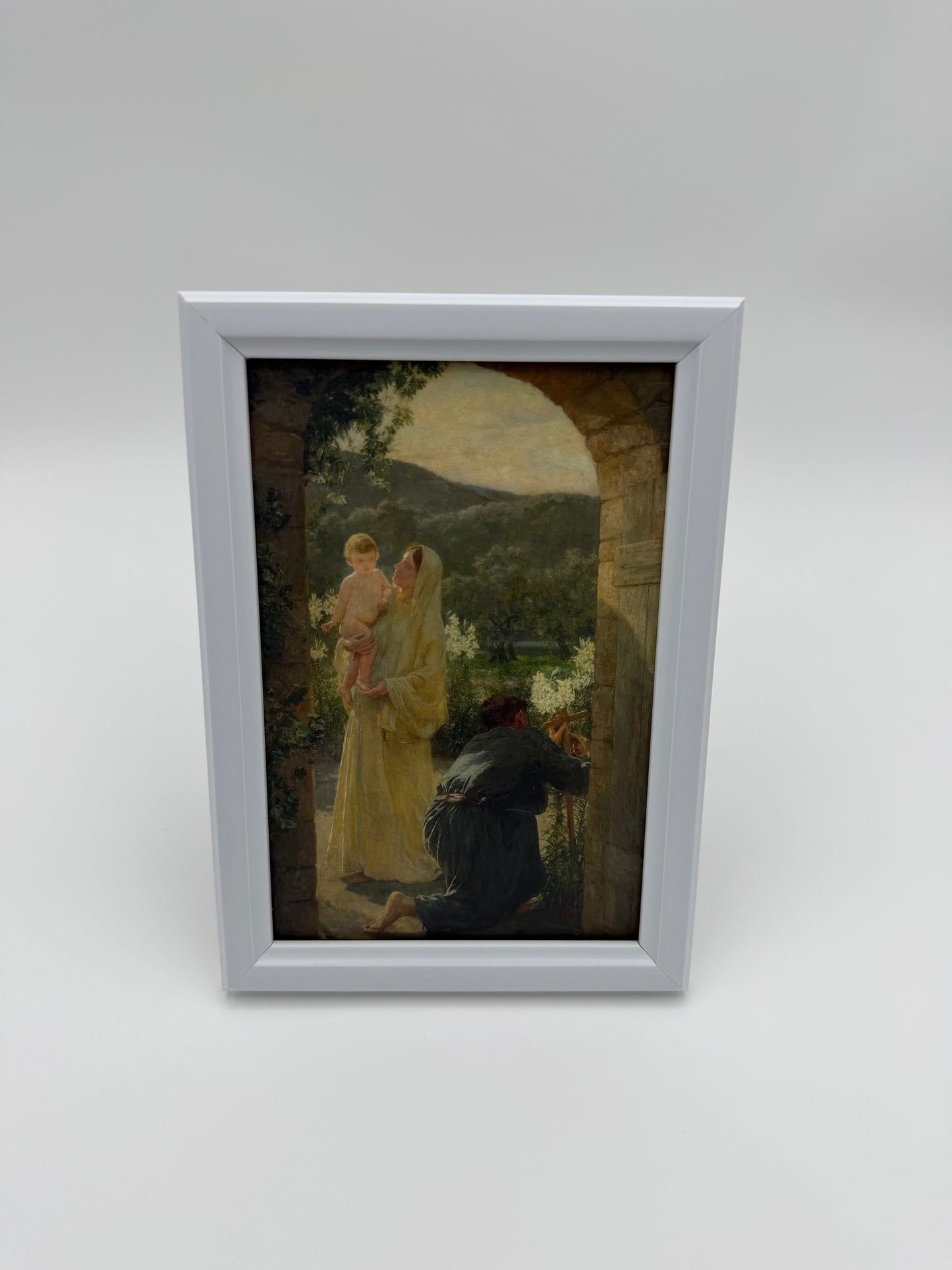 The image is a framed painting depicting a woman in a yellow dress and a child in a white dress, standing in a garden setting with a stone archway in the background.