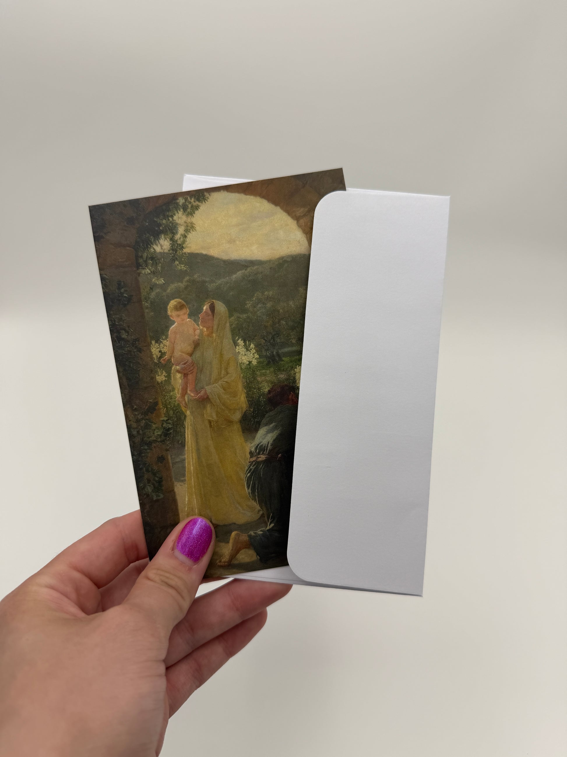 A hand holding a white envelope with a printed image of a woman in a yellow dress, against a white background.