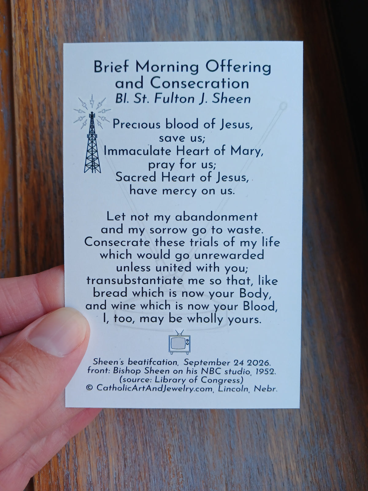 a person's hand holding a card with text and a small illustration of a radio tower.