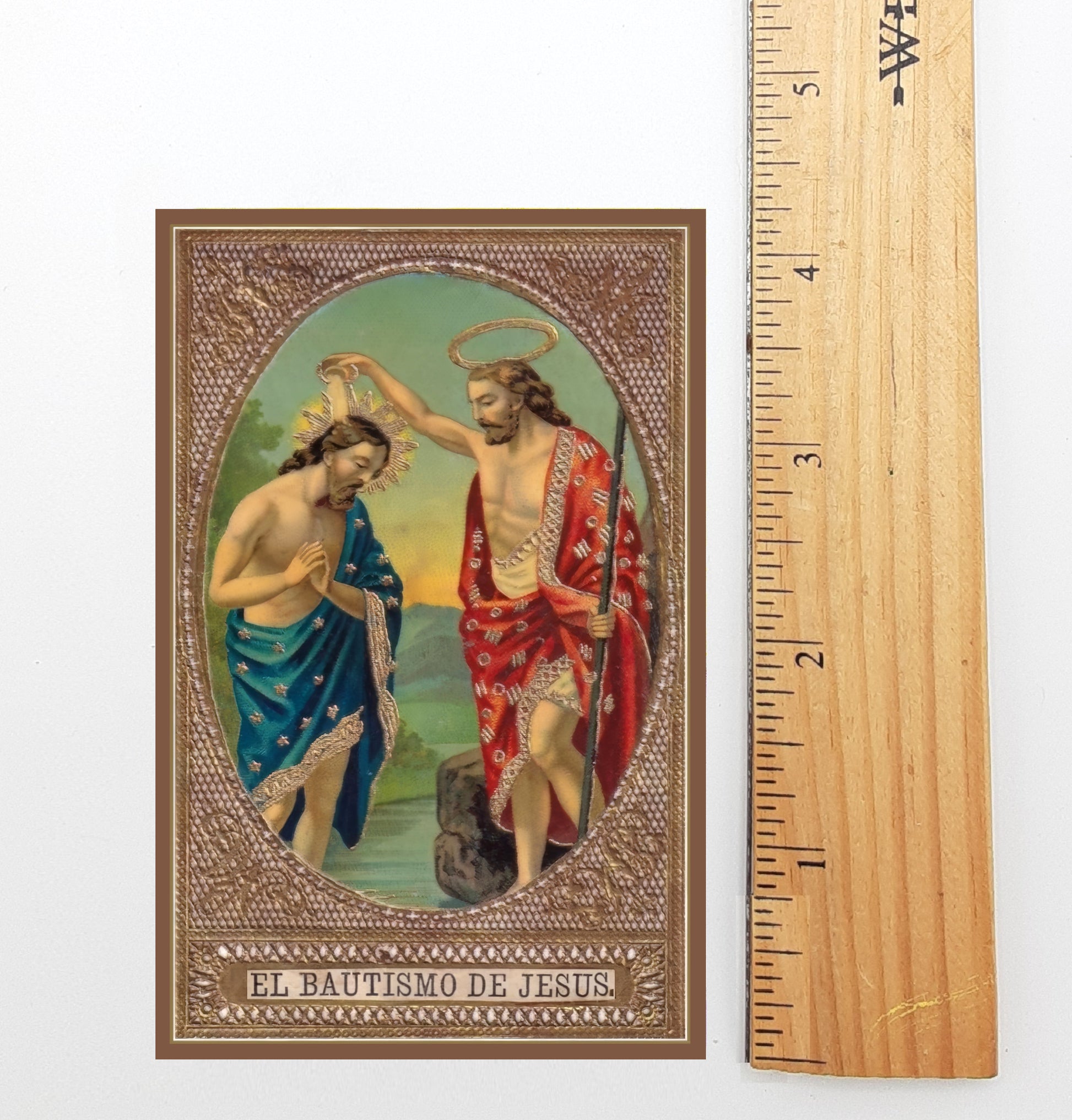The image is a religious painting depicting the baptism of Jesus, with a haloed figure and a figure in a red robe. The painting is framed and includes the text "EL BAUTISMO DE JESUS".