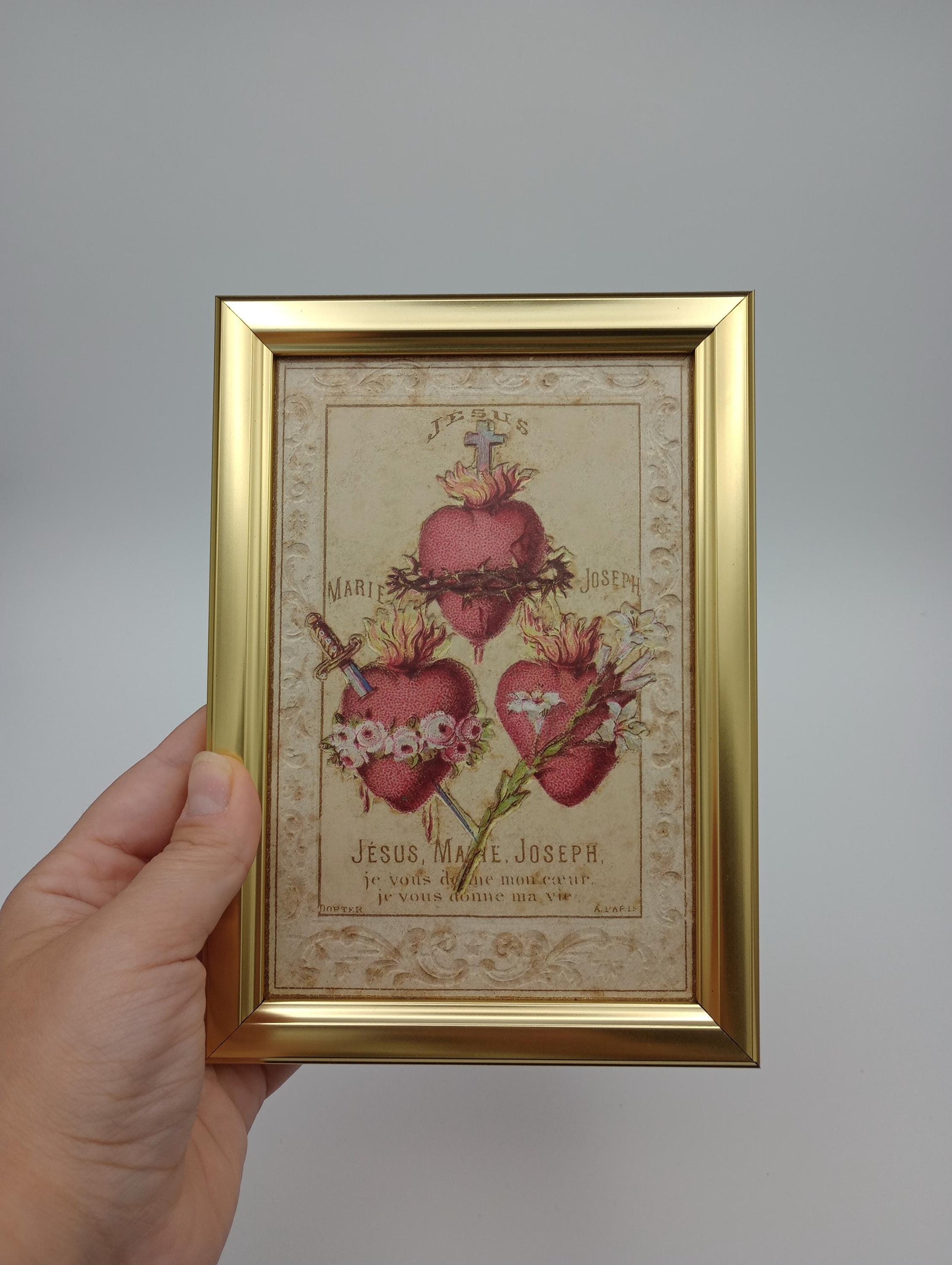 a hand holding a framed picture of flowers